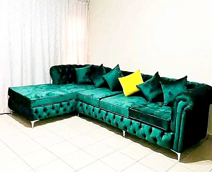Green emerald velvet Chesterfield-style L-shaped sectional sofa with tufted detailing.